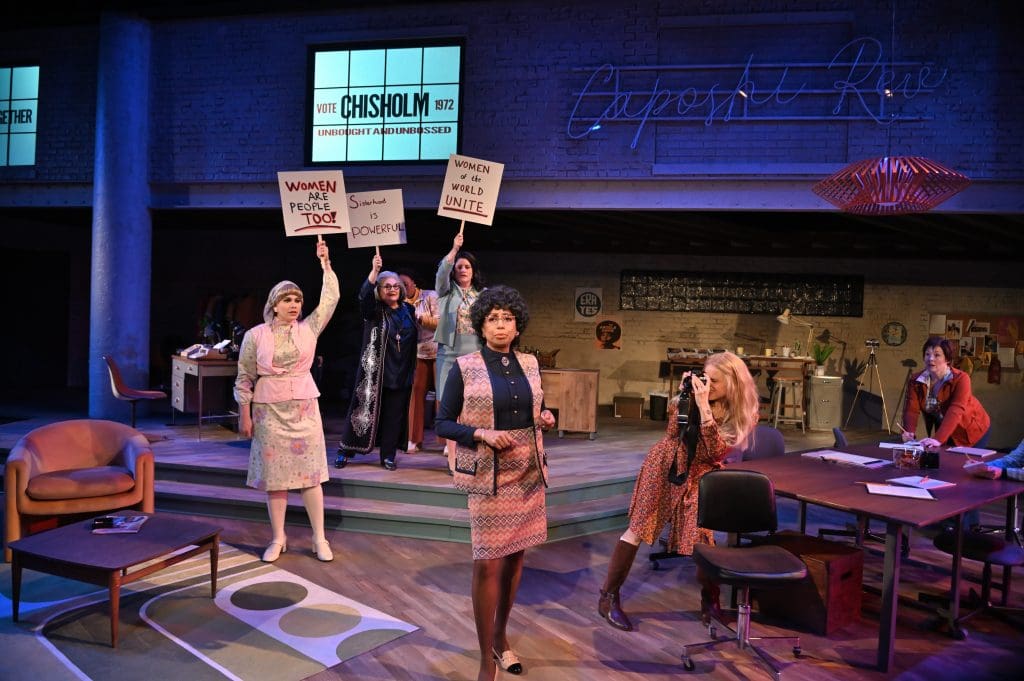 A group of women on a stage with protest signs.